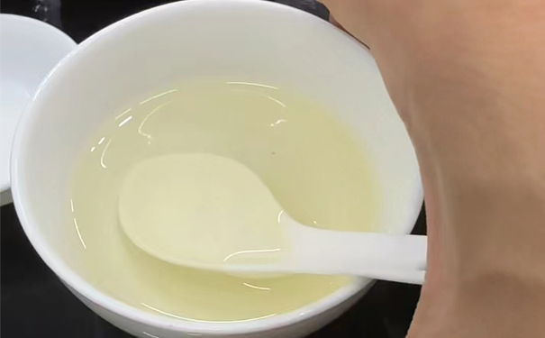 盛有勺子的二遍摇青淡黄色茶汤碗 一碗二遍摇青淡黄色茶汤