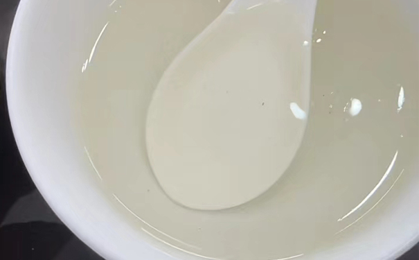 一遍摇青碗装茶汤与勺子 白色碗中盛着一遍摇青茶汤,内有勺子